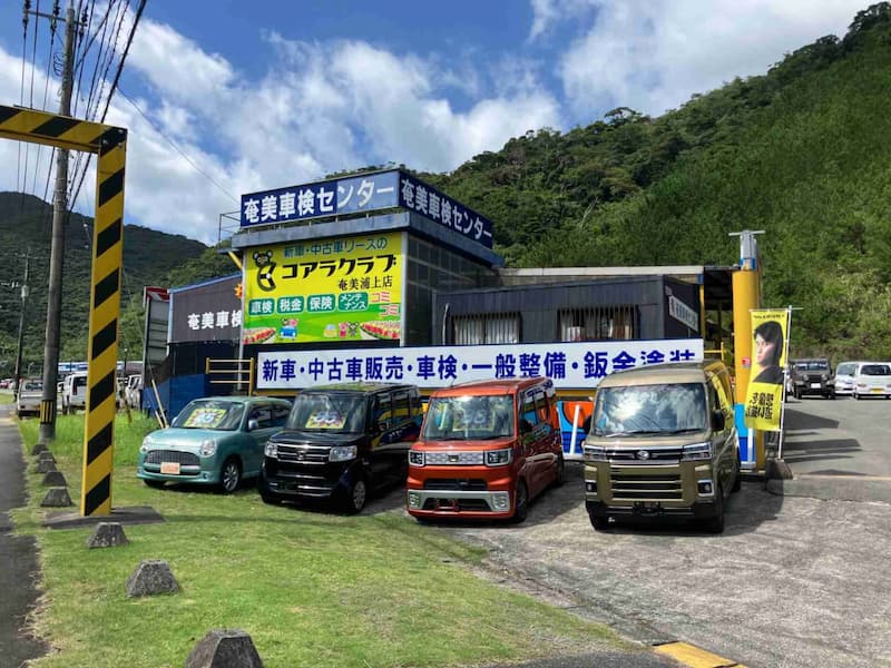 奄美車検センターの看板がある自動車販売店と展示車両